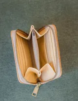 Billetera de cuero color tostado con cierre de cremallera. Interior con seis compartimentos para tarjetas y un compartimento para monedas con cierre. El billete entra doblado.