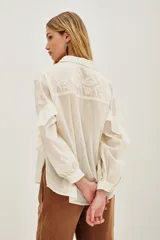 Camisa de algodón color blanco roto, con cuello camisero, mangas largas con volados y bordados florales en las mangas.