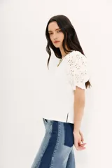 Remera blanca de algodón con calce al cuerpo, cuello redondo y tajos laterales. Mangas balloon con bordado tipo broderie.