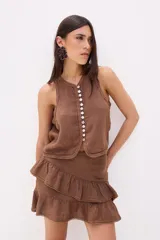 Top sin mangas color beige, con escote en V y cierre frontal de botones de nácar. Presenta costuras decorativas en el borde del escote y sisas.