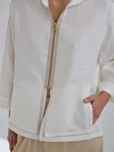 Chaqueta color beige de lino, con capucha, cierre frontal con cremallera negra, bolsillos laterales y mangas 3/4.