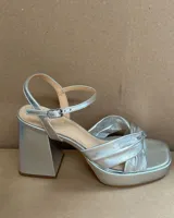 Sandalias plateadas de cuero vacuno con plataforma y tacón cuadrado. Tiras cruzadas en el empeine y pulsera con hebilla al tobillo. Tacón de 9.5 cm.