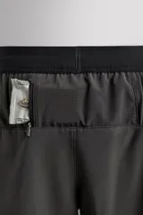 Shorts deportivos color verde oliva confeccionados en tejido técnico ligero y elástico. Cuenta con forro interior, cintura elástica ajustable con cordón, bolsillos laterales, bolsillo de seguridad en espalda con cierre de cremallera, bajo con aberturas laterales y logo estampado en la pierna.