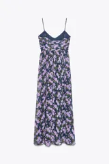 Vestido largo negro con estampado floral en tonos lila y verde. Escote en pico, tirantes finos, detalle drapeado en el busto, forro interior y cierre lateral con cremallera oculta.