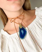 Collar con piedra azul en forma irregular, sujeto por un cordón de cuero.