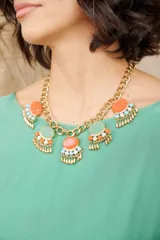 Collar dorado de cadena gruesa con dijes ovalados de color naranja y verde agua, decorados con piedras brillantes blancas, celestes y naranjas.