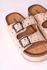 Sandalias beige con plataforma de corcho y doble tira con hebillas y tachas plateadas.