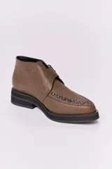 Botín acordonado de cuero marrón con textura grabada y hebilla lateral. Tiene suela de goma negra y puntera redondeada con costuras decorativas.