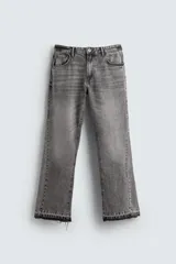 Pantalón de jean gris de corte flare, con cinco bolsillos, efecto lavado y bajo con acabado irregular.