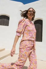 Pantalón de tiro medio con estampado floral en tonos rosa y naranja, corte semi-oxford con tajos en el bajo y botón de madera.