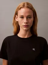 Remera negra de algodón con cuello redondo y mangas cortas. Presenta un logo bordado en el pecho.