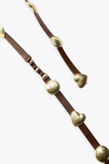 Cinturón marrón de cuero con apliques metálicos dorados en forma de círculos y corazones.
