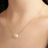 Collar dorado con dije de flor de nácar y mariposa con incrustaciones de strass.