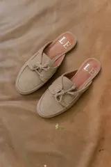 Mocasines tipo mule color beige, con detalle de cordones y ojales metálicos.
