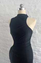 Vestido negro de fiesta, largo midi, con un solo hombro y abertura en la cintura.