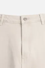 Bermuda color verde militar, de corte relaxed fit, con bolsillos frontales y traseros tipo plaqué, detalle de tira y bolsillo multifunción en la pierna, y bajo irregular.