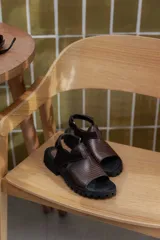 Sandalias marrones con tiras de cuero texturizado y suela track negra.