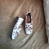 Mocasines de cuero con estampado animal print de vaca, con borlas decorativas y suela plana.