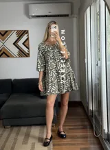 Vestido corto color verde oliva con estampado de hojas en blanco y negro, escote con lazo ajustable y mangas 3/4 acampanadas.