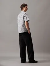 Camisa de manga corta con cuello cubano y corte boxy. Diseño con estampado de rejilla en blanco y negro y logo de Calvin Klein estampado.