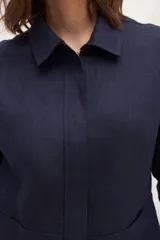 Chaqueta color crema de lino, de corte recto, con cuello camisero y cierre frontal con botones.