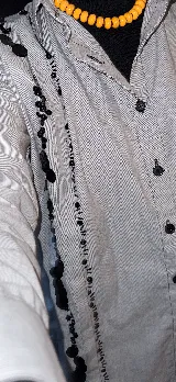 Camisa celeste a rayas verticales con bordado de mostacillas negras en los alforzas. De corte oversized y manga larga.