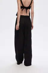 Pantalón negro de viscosa, corte ancho y tiro alto, con elástico en la cintura y bolsillos laterales.