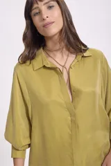 Camisa color verde oliva, de corte recto, con cuello camisero y mangas largas con puños abotonados.