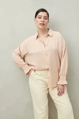 Camisa negra de manga larga con cuello clásico y botones frontales. El tejido presenta una textura arrugada o plisada, y los puños tienen un detalle fruncido o elástico.