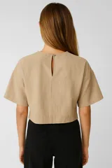 Blusa holgada de algodón color verde militar, con cuello a la base y abertura frontal con botones. Presenta mangas cortas amplias.