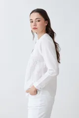Camisa blanca de manga larga con bordados en el frente y cuello.