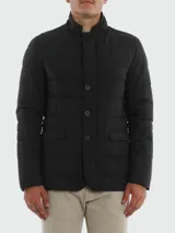 Chaqueta de vestir negra acolchada con relleno de plumas y cuello mao. Presenta cierre frontal con botones, un bolsillo en el pecho y dos bolsillos laterales con solapa. Fabricada en tejido Gortex.