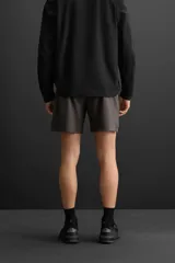 Shorts deportivos color gris oscuro confeccionados en tejido técnico ligero y elástico con forro interior, cintura elástica ajustable con cordón, bolsillos laterales, bolsillo de seguridad en espalda con cierre de cremallera, bajo con aberturas laterales y detalle de logo estampado en pernera.
