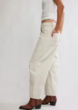 Pantalón de jean color crema, de corte relajado, piernas anchas y tiro medio. Tiene una silueta distinta y un largo hasta los tobillos.