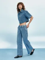 Camisa de denim celeste con corte cropped, mangas cortas y bolsillo en el pecho.