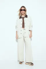 Sobrecamisa tipo barn jacket color negro, de algodón con elastano, con silueta relajada y estructura firme. Presenta cierre frontal con botones metálicos, cuello marrón, bolsillos aplicados y pespuntes visibles en color marrón.