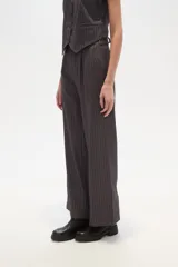 Pantalón de poliéster negro con rayas verticales blancas, de corte recto y tiro alto.