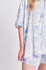 Camisa oversize de manga corta con estampado de palmeras y limones en tonos azules sobre fondo blanco. Confeccionada en lino.