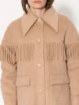 Tapado de paño color beige con flecos en la parte superior y broches al tono. Forrería estampada con print de monas. Diseño de la colaboración entre Jazmin Chebar y Edgardo Giménez.