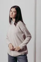 Sweater color crema de tejido de punto con hilos metalizados, corte relajado, hombros caídos y terminaciones clásicas.