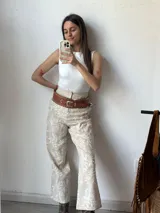Pantalón de vestir color crudo con bordado floral blanco.