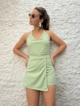 Mono corto color verde, con escote halter y falda cruzada.