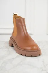 Bota Chelsea de cuero color marrón, con elásticos laterales y suela track.