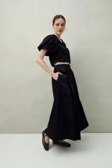 Falda midi blanca con pequeños lunares negros, de corte acampanado y cintura alta con pliegues.