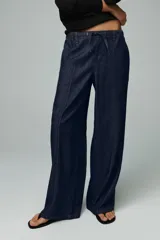 Pantalón de jean azul oscuro, de tiro alto y pierna ancha, con cintura elástica ajustable con cordones y bolsillos delanteros.