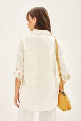 Campera manga larga color marrón con cuello camisero, confeccionada en gabardina con parches bordados en delantero y espalda.