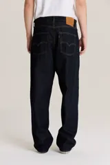 Pantalón de jean azul oscuro, corte amplio, con bolsillos delanteros y traseros.