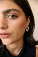 Aros de acero quirúrgico hipoalergénico con forma de argolla plateada y dije circular colgante de piedra natural color azul.