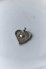 Collar con tiento encerado negro y dije dorado con forma de corazón texturizado.