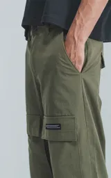 Pantalón verde militar de corte recto con bolsillos cargo laterales y etiqueta con logo en la pierna derecha.